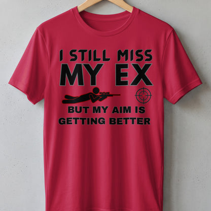 Red t-shirt with "I STILL MISS MY EX BUT MY AIM IS GETTING BETTER" text.