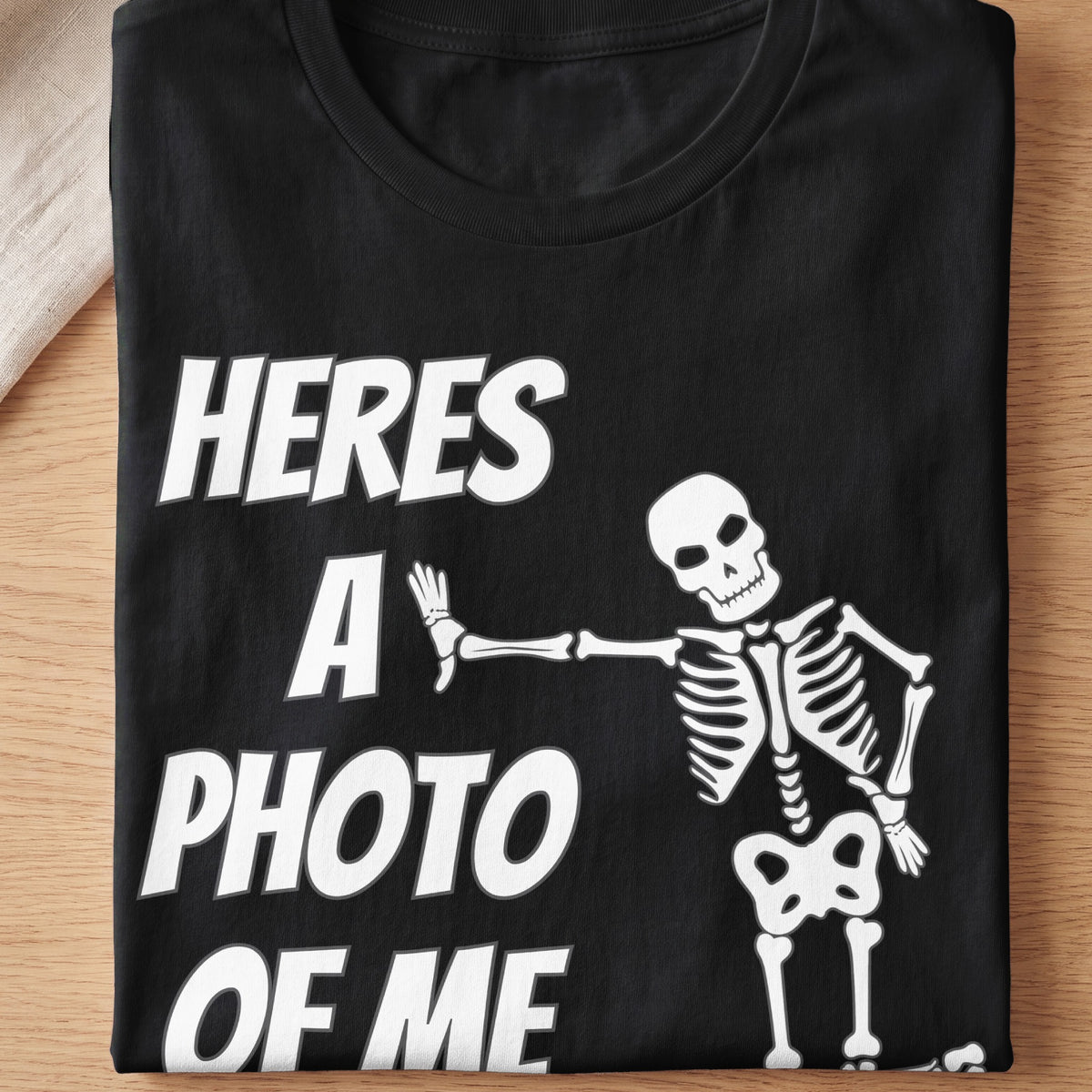 Black t-shirt with white text "heres a photo of me" and a skeleton graphic.