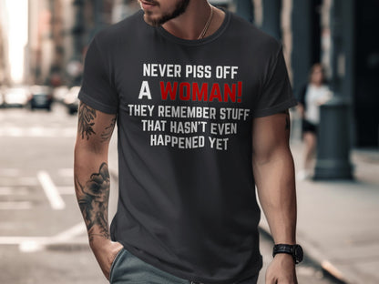 Dark t-shirt with text: "NEVER PISS OFF A WOMAN! THEY REMEMBER STUFF THAT HASN'T EVEN HAPPENED YET"