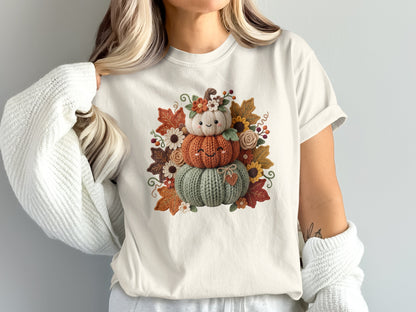 T-shirt with stacked knit pumpkins, flowers, and autumn leaves graphic.