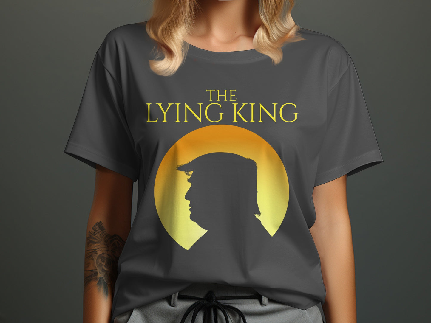 Dark grey t-shirt with yellow text "THE LYING KING" above a silhouette of Donald Trump.