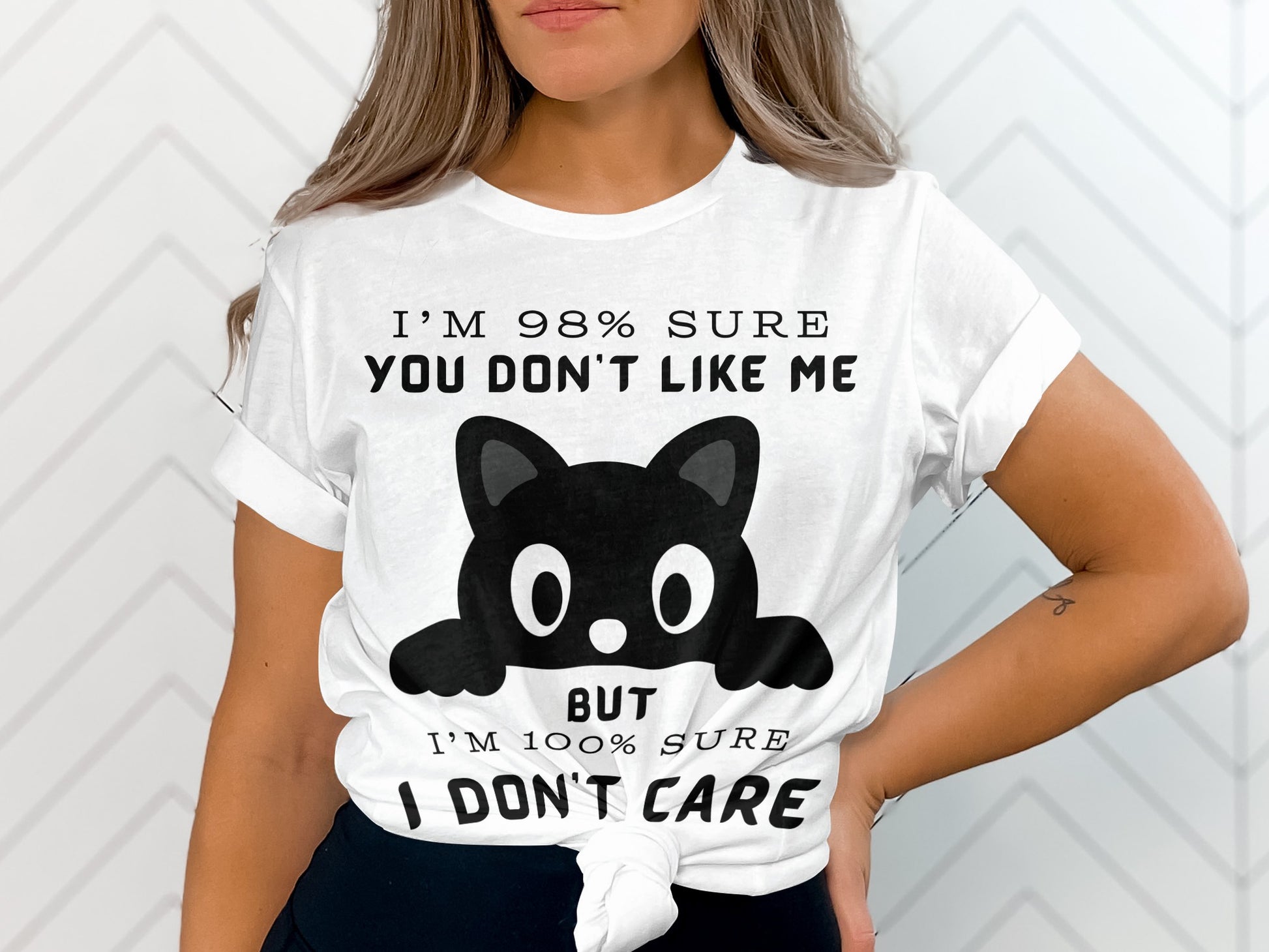 White t-shirt with a black cat graphic and text: "I'm 98% sure you don't like me but I'm 100% sure I don't care."