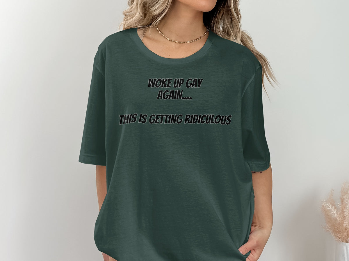 Dark green t-shirt with black text reading "WOKE UP GAY AGAIN.... THIS IS GETTING RIDICULOUS."