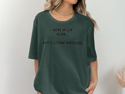 Dark green t-shirt with black text reading "WOKE UP GAY AGAIN.... THIS IS GETTING RIDICULOUS."
