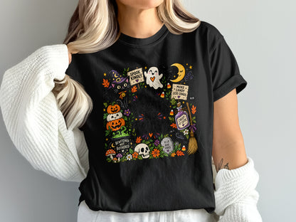Black t-shirt with a colorful Halloween graphic featuring a black cat, pumpkins, ghost, moon, and text.