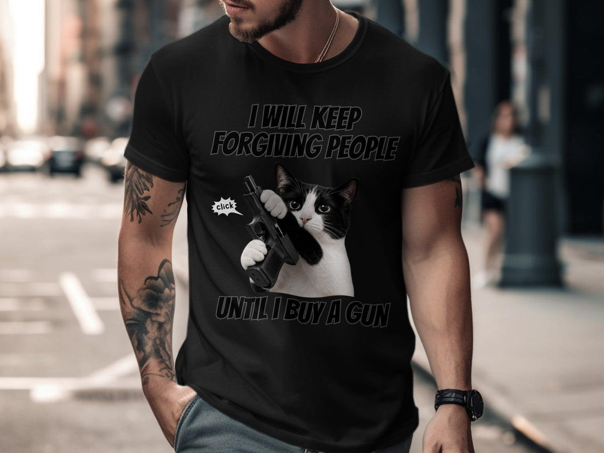 Black t-shirt with cat holding a gun, text says "I WILL KEEP FORGIVING PEOPLE UNTIL I BUY A GUN".