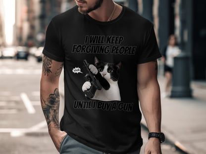 Black t-shirt with cat holding a gun, text says "I WILL KEEP FORGIVING PEOPLE UNTIL I BUY A GUN".
