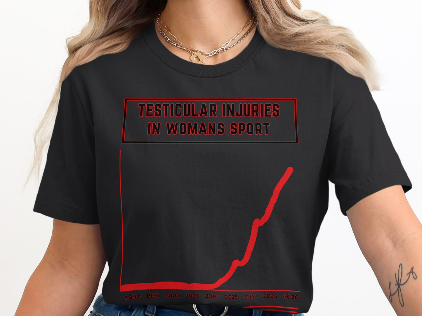 Black t-shirt with red text "TESTICULAR INJURIES IN WOMANS SPORT" and a red graph.