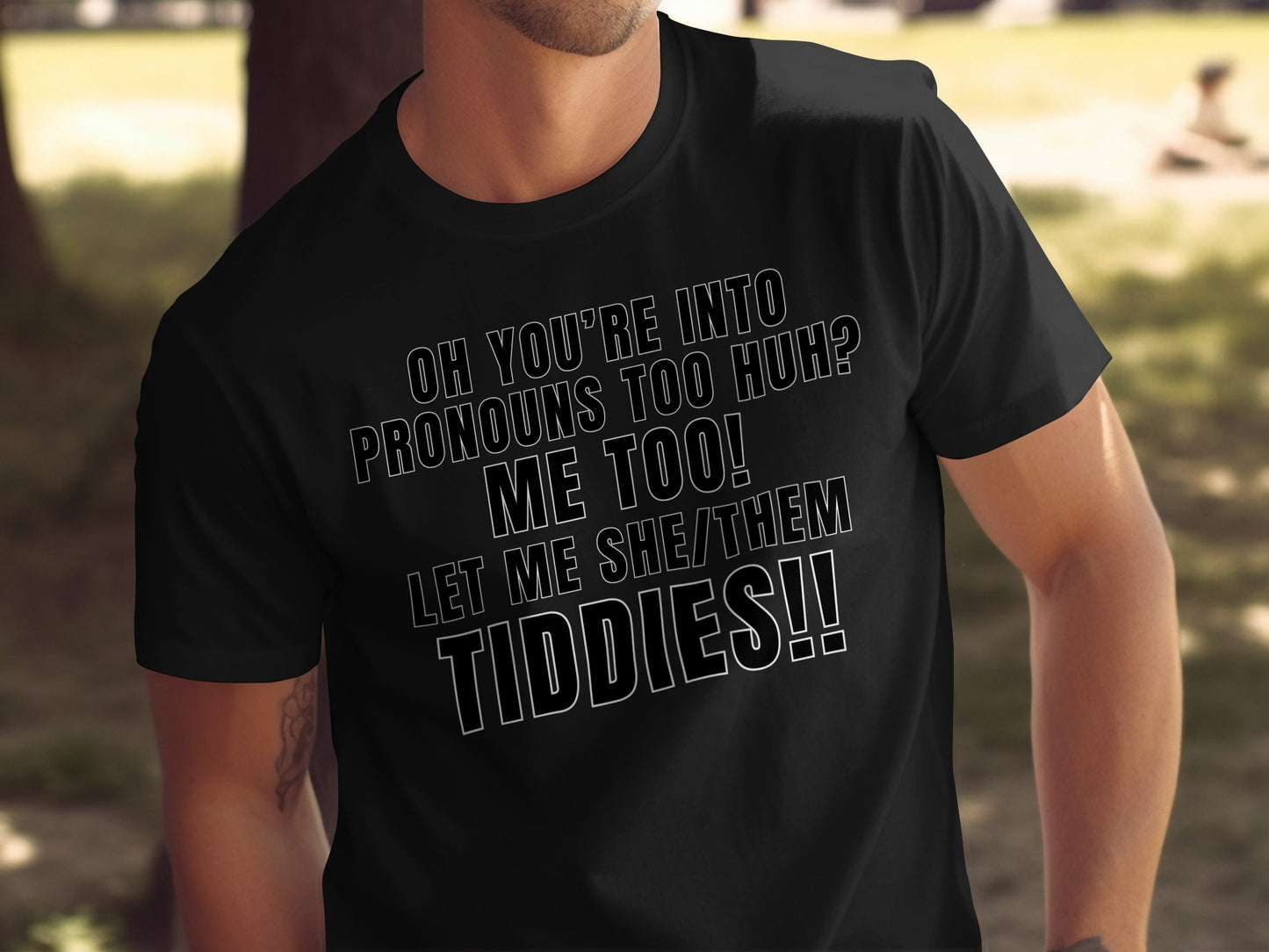 Black t-shirt with text: "Oh you're into pronouns too huh? Me too! Let me she/them tiddies!!"