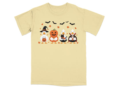 Four ducks in Halloween costumes: witch, pumpkin, cat, and vampire on a tan t-shirt.