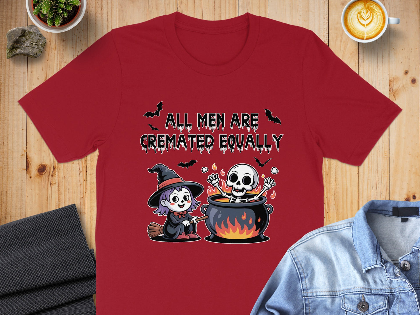 Red t-shirt with cartoon witch, skeleton in cauldron, and text "All Men Are Cremated Equally".