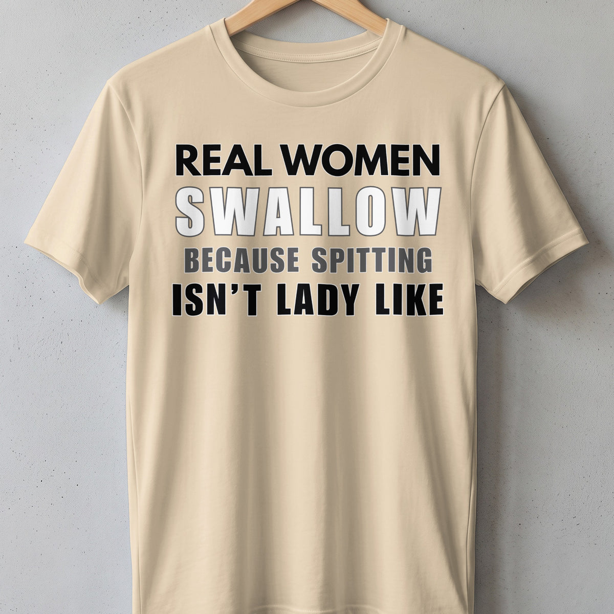 Light tan t-shirt with text: "REAL WOMEN SWALLOW BECAUSE SPITTING ISN'T LADY LIKE"