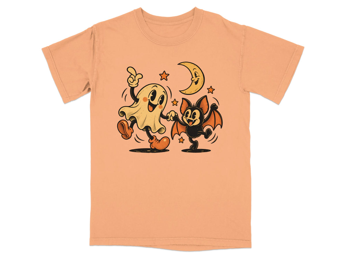 Peach t-shirt with cartoon ghost and bat dancing under a crescent moon.