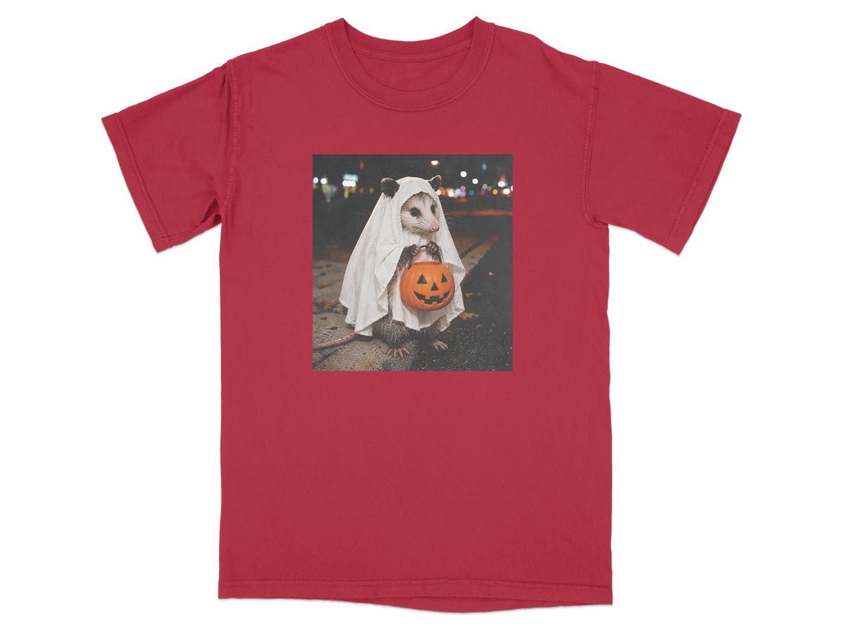 Opossum in ghost costume holding a jack-o'-lantern on a red t-shirt.
