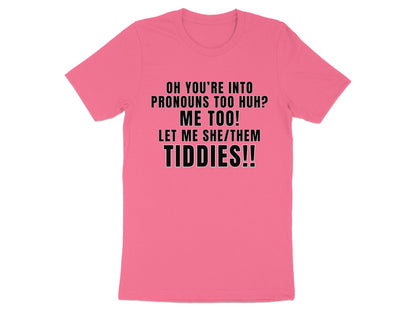 Pink t-shirt with black text "OH YOU'RE INTO PRONOUNS TOO HUH? ME TOO! LET ME SHE/THEM TIDDIES!!"