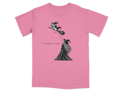 Pink t-shirt featuring a black and white graphic of a witch and a dog riding a broomstick.