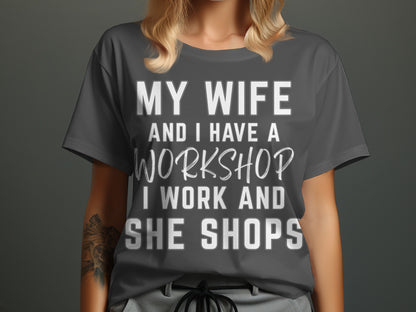 Dark gray t-shirt with white text: MY WIFE AND I HAVE A WORKSHOP. I WORK AND SHE SHOPS.