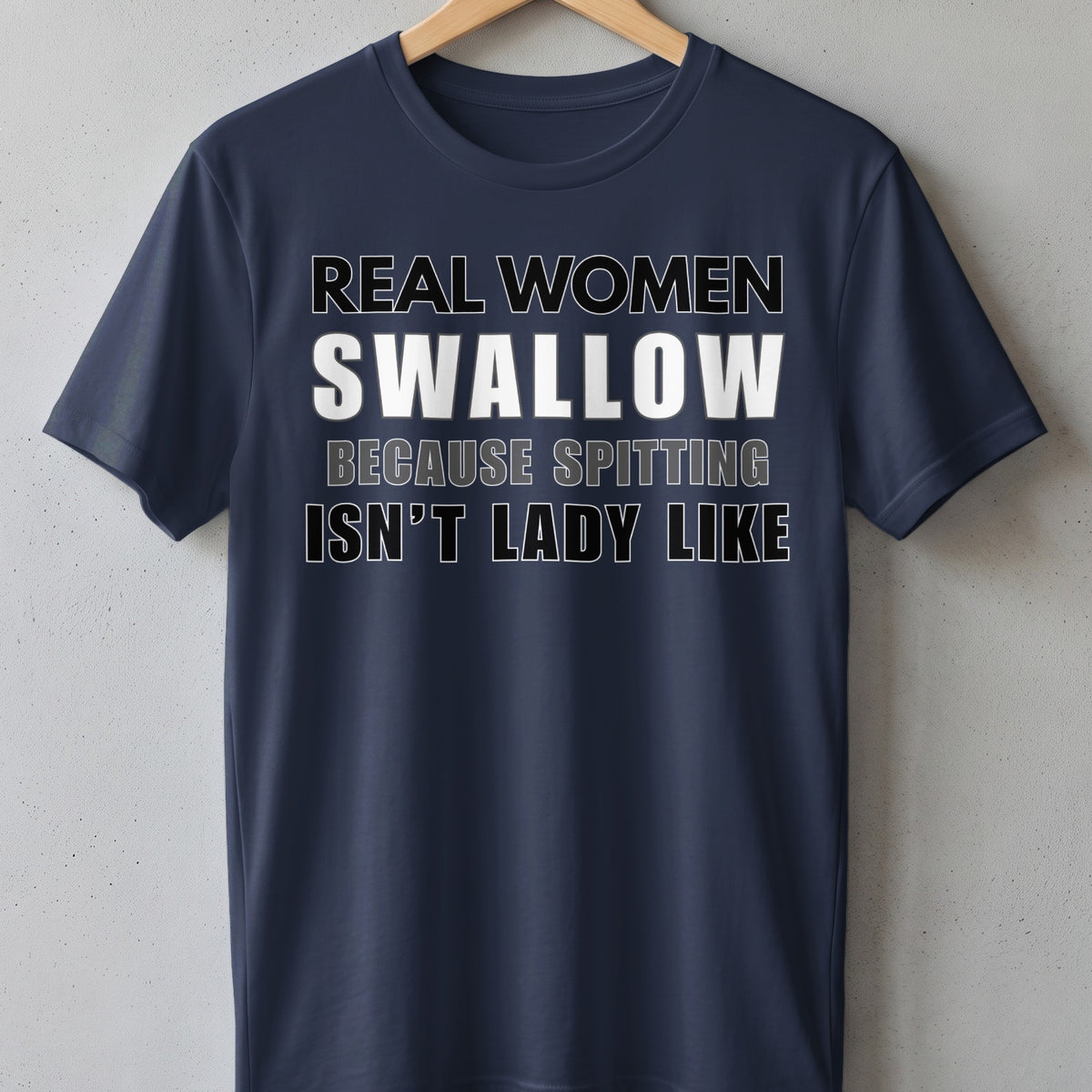 Navy t-shirt with white and grey text that reads "Real women swallow because spitting isn't lady like."