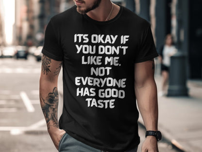 Black t-shirt with white text reading "ITS OKAY IF YOU DON'T LIKE ME, NOT EVERYONE HAS GOOD TASTE."