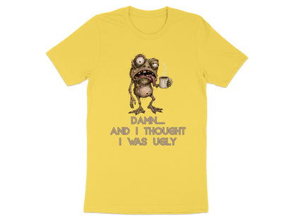Yellow t-shirt with a cartoon monster holding a coffee mug and text that reads "Damn.... and I thought I was ugly."