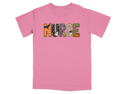 A pink short-sleeved t-shirt featuring the word NURSE in patterned Halloween-themed block letters across the chest.