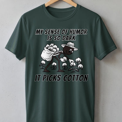 Dark humor t-shirt with illustration of person picking cotton and text "MY SENSE OF HUMOR IS SO DARK IT PICKS COTTON".