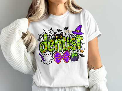 A person wearing a white t-shirt featuring a green Halloween-themed dentist graphic with ghosts, bats, and a witch hat.