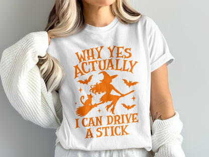 White t-shirt with orange Halloween graphic: witch, cat, bats, and text "Why Yes Actually I Can Drive A Stick".