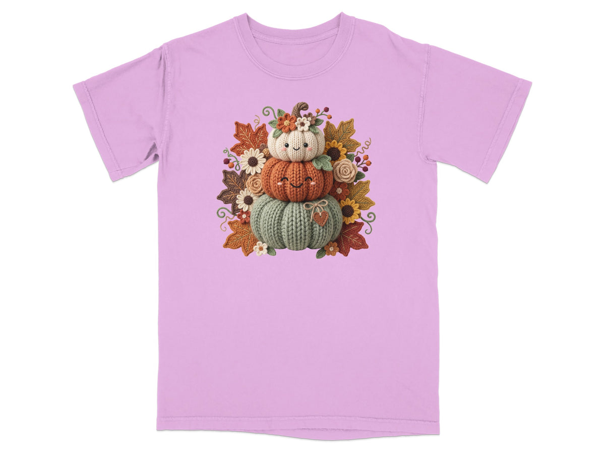 Knitted pumpkin stack with autumn leaves and flowers on a pink t-shirt.