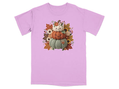 Knitted pumpkin stack with autumn leaves and flowers on a pink t-shirt.