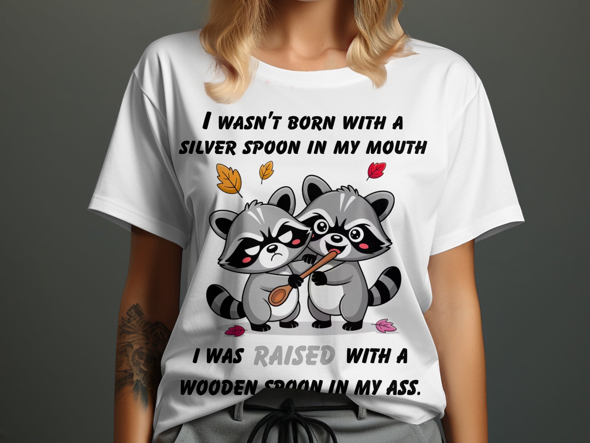 Two raccoons with a wooden spoon, text reads "I WASN'T BORN WITH A SILVER SPOON IN MY MOUTH. I WAS RAISED WITH A WOODEN SPOON IN MY ASS."