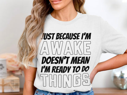 White t-shirt with text: JUST BECAUSE I'M AWAKE DOESN'T MEAN I'M READY TO DO THINGS.