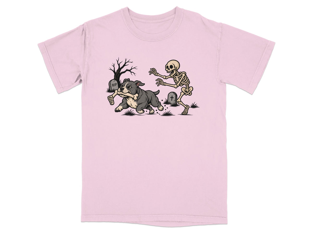 A light pink t-shirt featuring a cartoon graphic of a skeleton chasing a dog holding a bone.