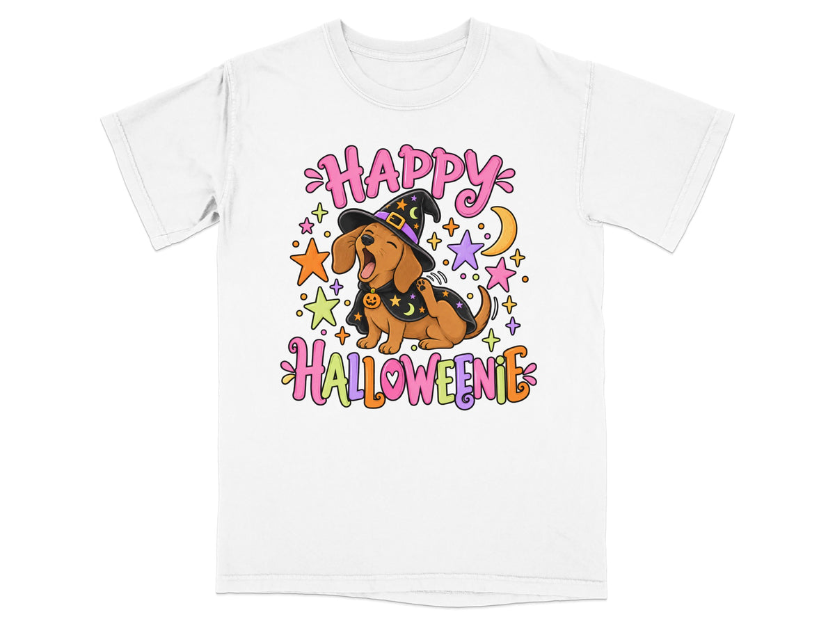 A white t-shirt featuring a cartoon dachshund in a witch hat and cape, with the text "HAPPY HALLOWEENIE".