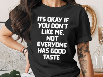 Black t-shirt with white text that reads "ITS OKAY IF YOU DON'T LIKE ME. NOT EVERYONE HAS GOOD TASTE."