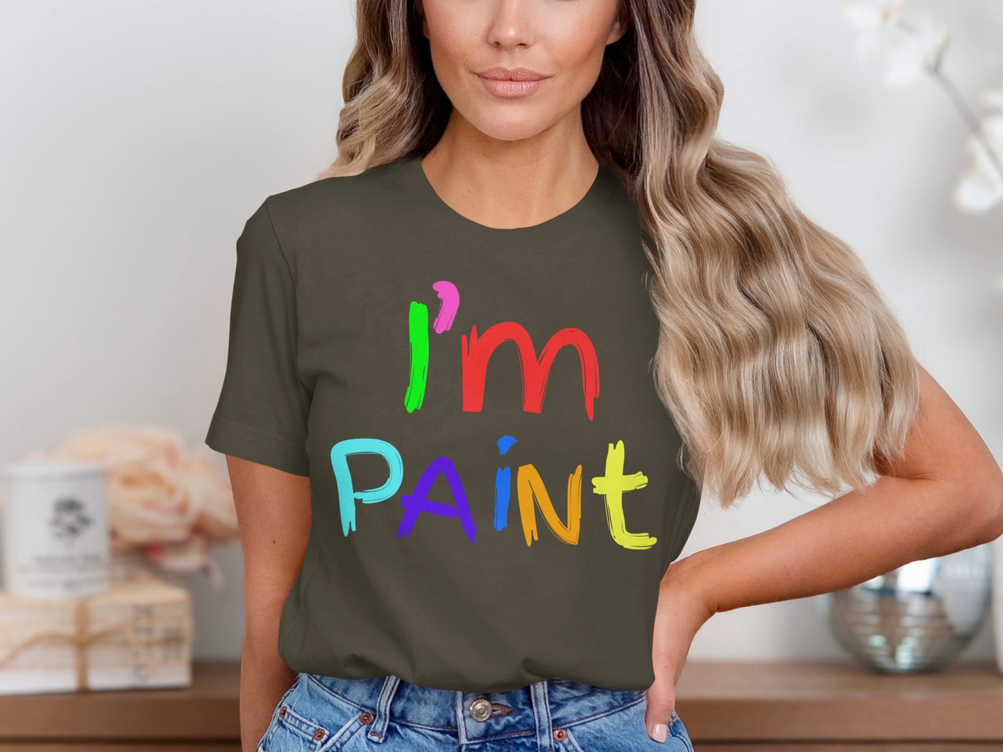 Woman wearing a dark green t-shirt with colorful "I'm PAINT" text graphic.