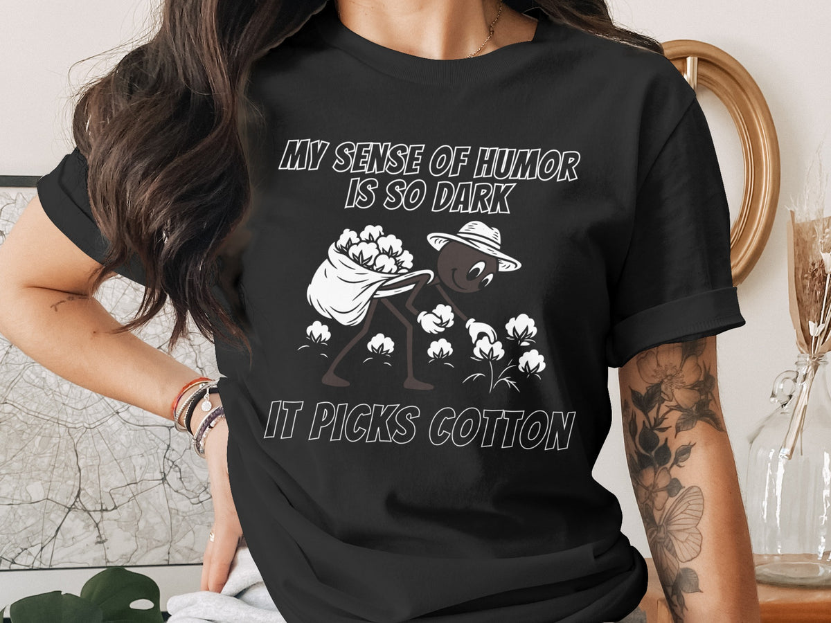 Black t-shirt with cartoon ant picking cotton and text "MY SENSE OF HUMOR IS SO DARK IT PICKS COTTON".