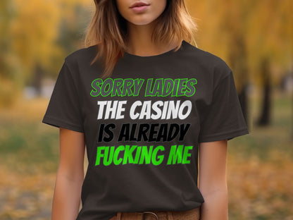 Dark t-shirt with text "SORRY LADIES THE CASINO IS ALREADY FUCKING ME".