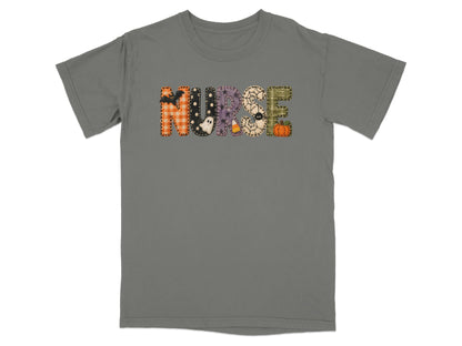 A grey short-sleeve t-shirt with the word NURSE spelled out in patterned Halloween-themed letters across the chest.