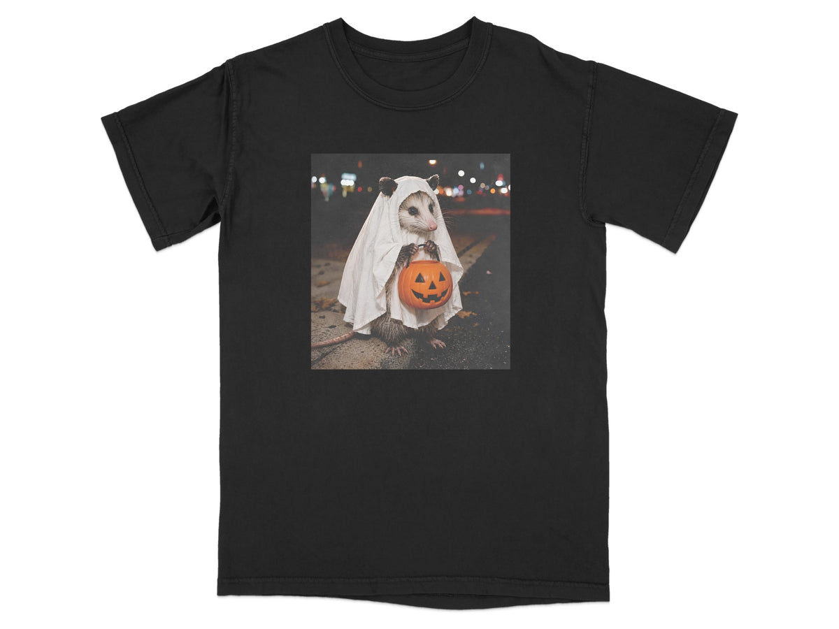 Opossum in ghost costume holding a jack-o'-lantern on a dark street.