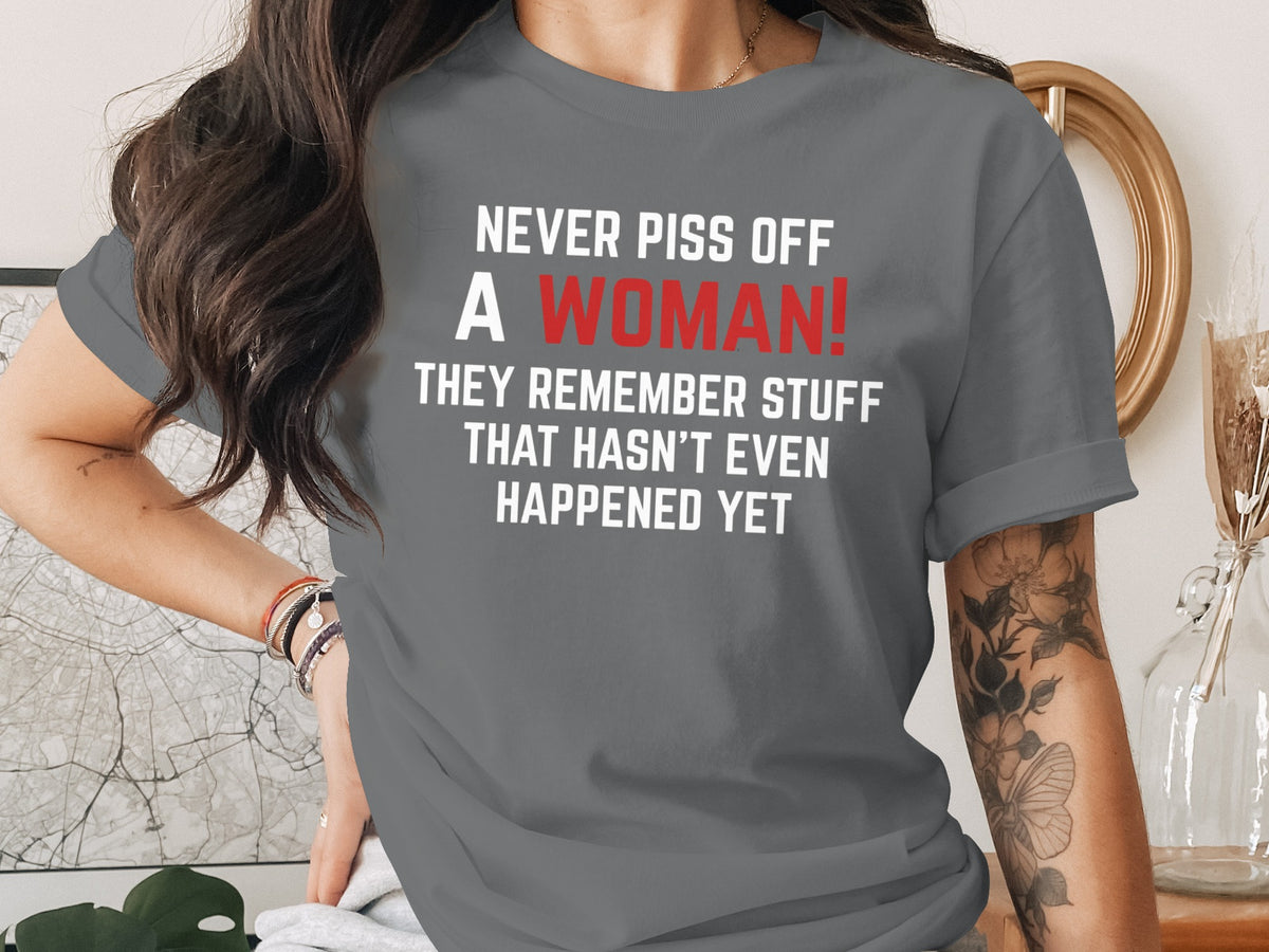 Gray t-shirt with white text: "NEVER PISS OFF A WOMAN! THEY REMEMBER STUFF THAT HASN'T EVEN HAPPENED YET".