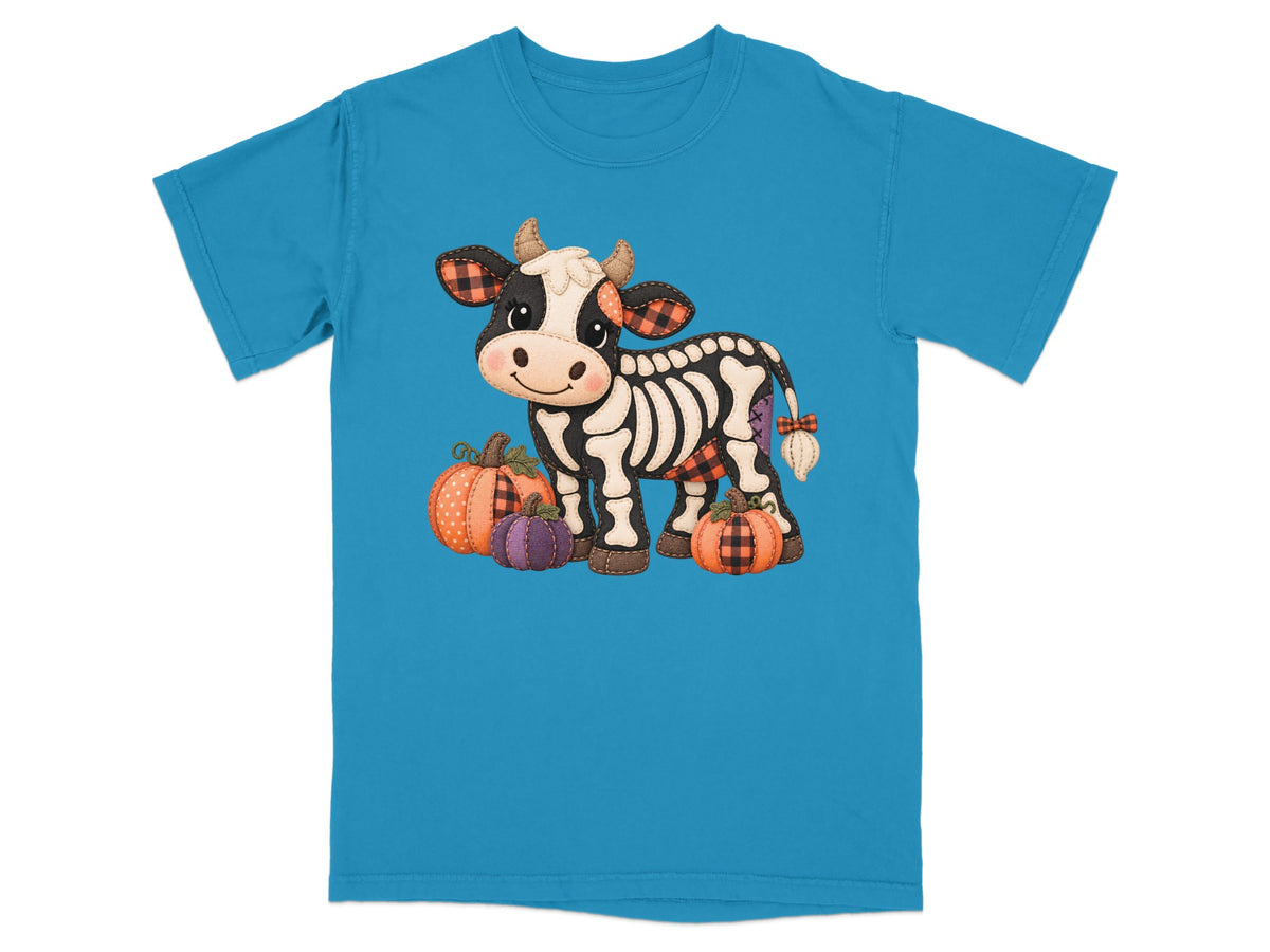 Skeleton cow with plaid accents and pumpkins on a blue t-shirt.