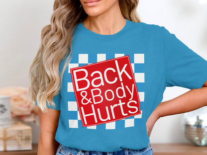 Blue t-shirt with white text "Back & Body Hurts" on a red square over a checkerboard pattern.