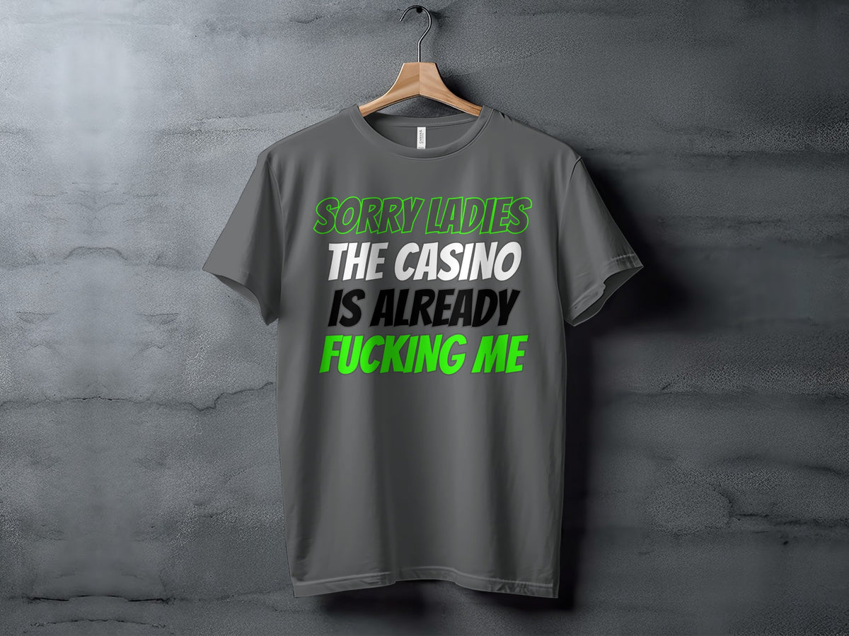 Grey t-shirt with text "Sorry Ladies The Casino Is Already Fucking Me" in green and white.