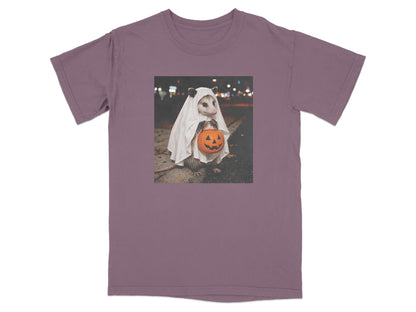 Opossum in ghost costume holding a jack-o'-lantern on a street at night.