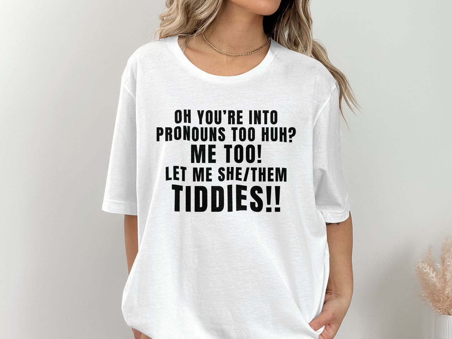 White t-shirt with black text reading "OH YOU'RE INTO PRONOUNS TOO HUH? ME TOO! LET ME SHE/THEM TIDDIES!!"