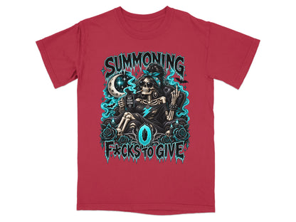 A red short-sleeve t-shirt featuring a graphic of a skeleton sitting in a chair, surrounded by blue glowing smoke, roses, and the text "SUMMONING 0 F*CKS TO GIVE".