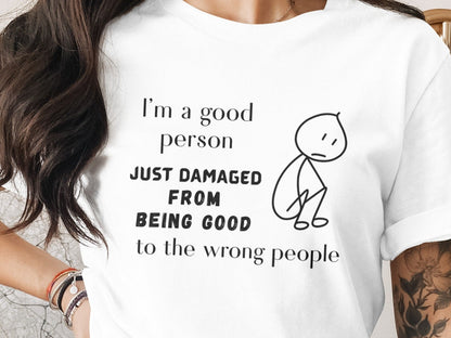 White t-shirt with text "I'm a good person JUST DAMAGED FROM BEING GOOD to the wrong people" and stick figure.