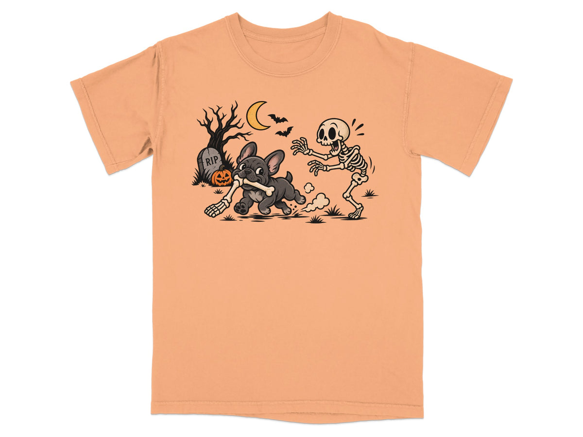 French bulldog chases skeleton with bone on peach t-shirt with Halloween background.