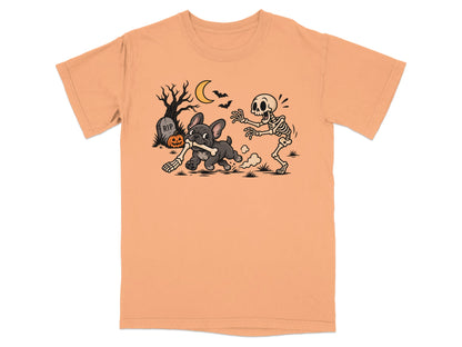 French bulldog chases skeleton with bone on peach t-shirt with Halloween background.